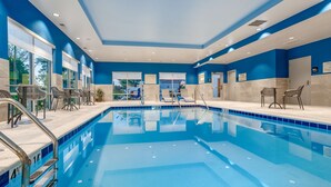 Une piscine à l’eau d’un bleu cristallin, entourée de chaises longues et bordée d’une terrasse carrelée.