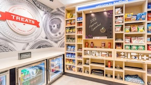 Une chambre d’hôtel équipée d’un mini-bar, d’un réfrigérateur pour le mini-bar, et d’un mur décoré d’une grande horloge et d’une enseigne sur laquelle on peut lire : « Bienvenue à Bedford ».