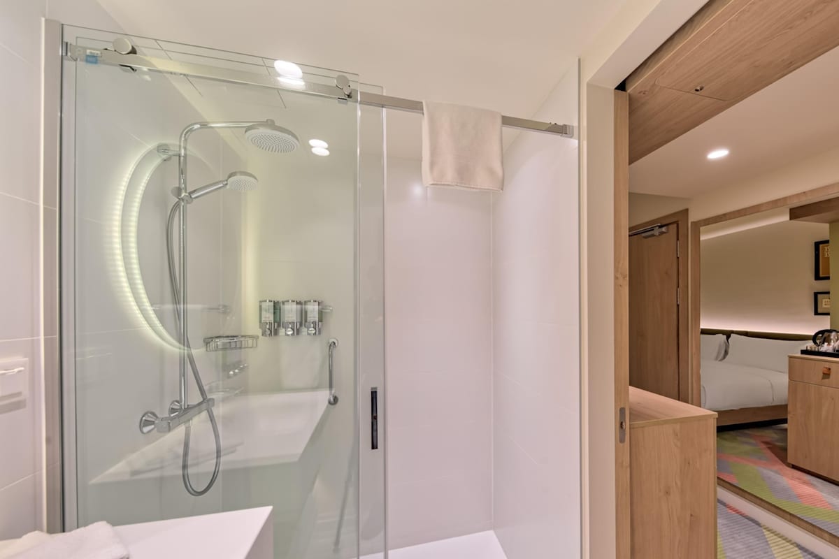A modern bathroom with a glass-enclosed shower, a white sink, and a wooden vanity.