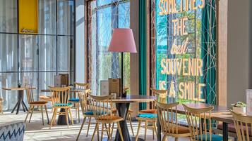 A modern interior with wooden chairs and tables, large windows, and a motivational sign.