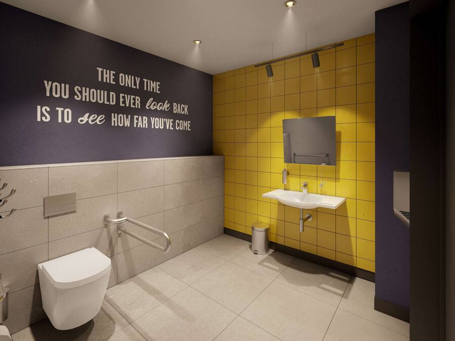 Une salle de bain moderne équipée de toilettes, d’un lavabo et de barres d’appui.