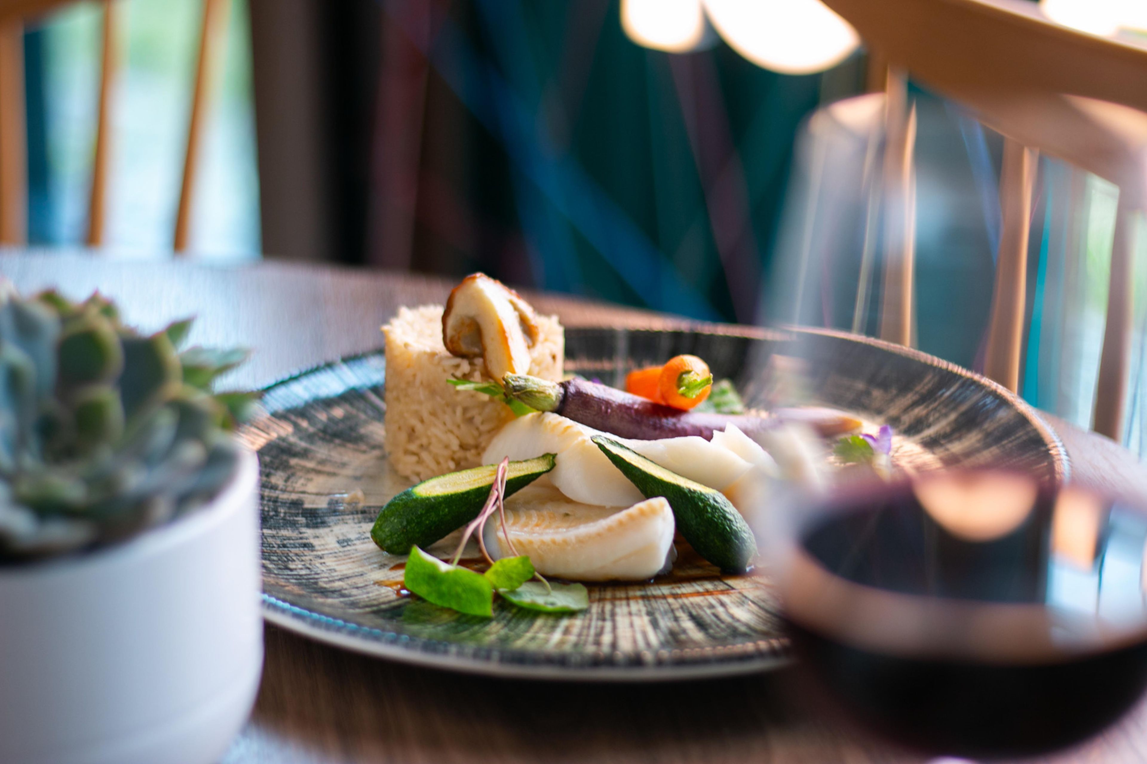 A plate with food items and a glass of red liquid, possibly wine, on a table.