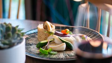 A plate with food items and a glass of red liquid, possibly wine, on a table.