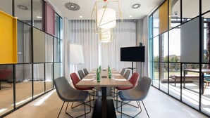 A modern conference room with a long table, chairs, and a large screen.