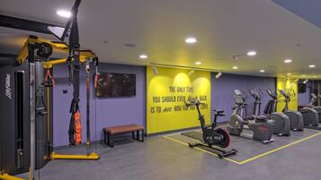 Un gimnasio con equipo de ejercicio, una banca y un letrero motivacional en la pared.