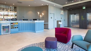 A modern lobby with a bar area, seating, and an elevator.