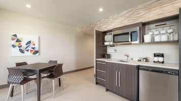 A modern kitchen with a dining area, featuring a microwave, coffee maker, and cabinets.