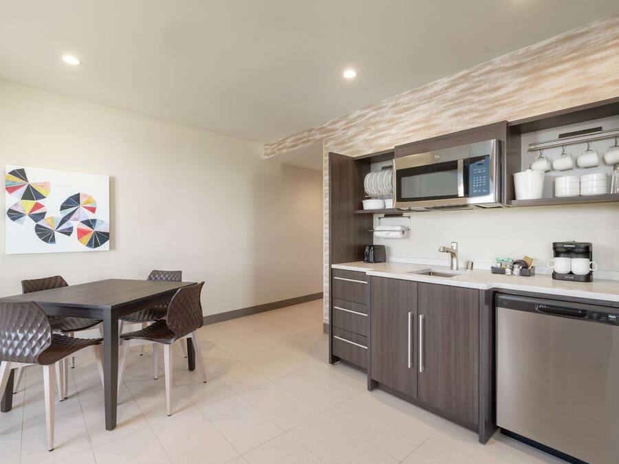 A modern kitchen with a dining area, featuring a microwave, coffee maker, and cabinets.