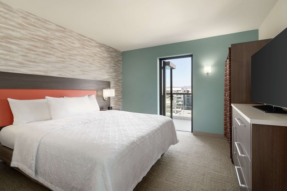 Habitación de hotel con cama, escritorio, televisor y vista de la ciudad.