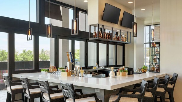 Una cocina moderna con una isla grande, taburetes de bar y una estantería para vinos.