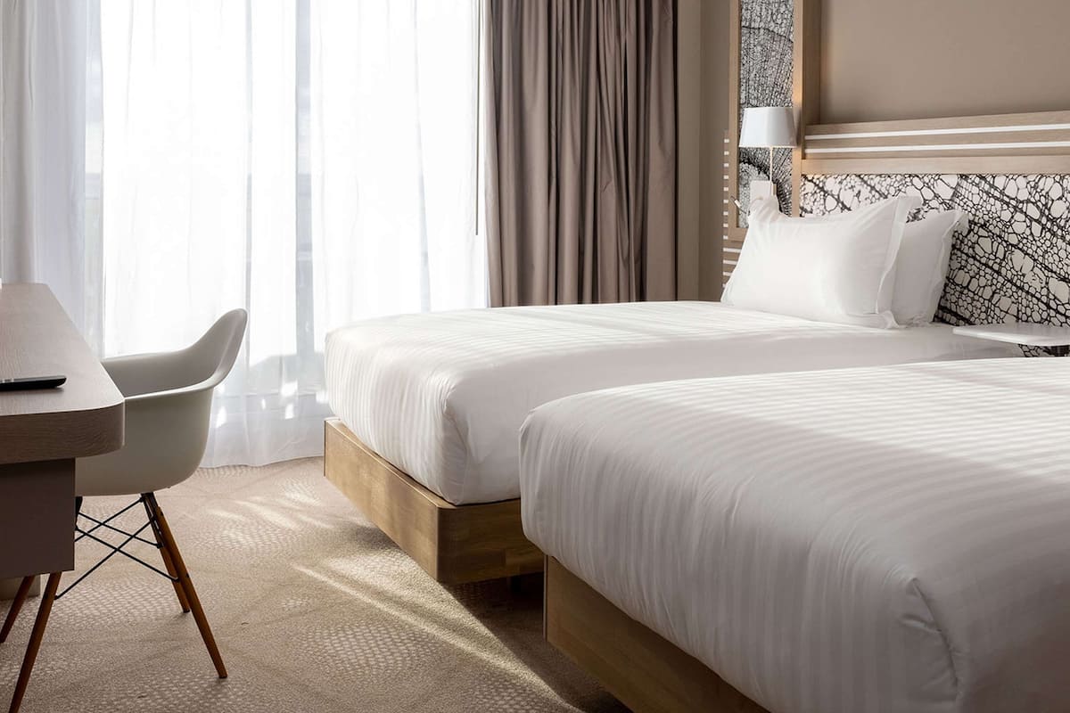 Une chambre d’hôtel avec deux lits, un bureau et une chaise.