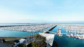 A marina with numerous boats docked, a clear sky, and a distant lighthouse.