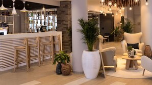 Un espace bar moderne avec des chaises en bois, une grande plante en pot et des luminaires suspendus.