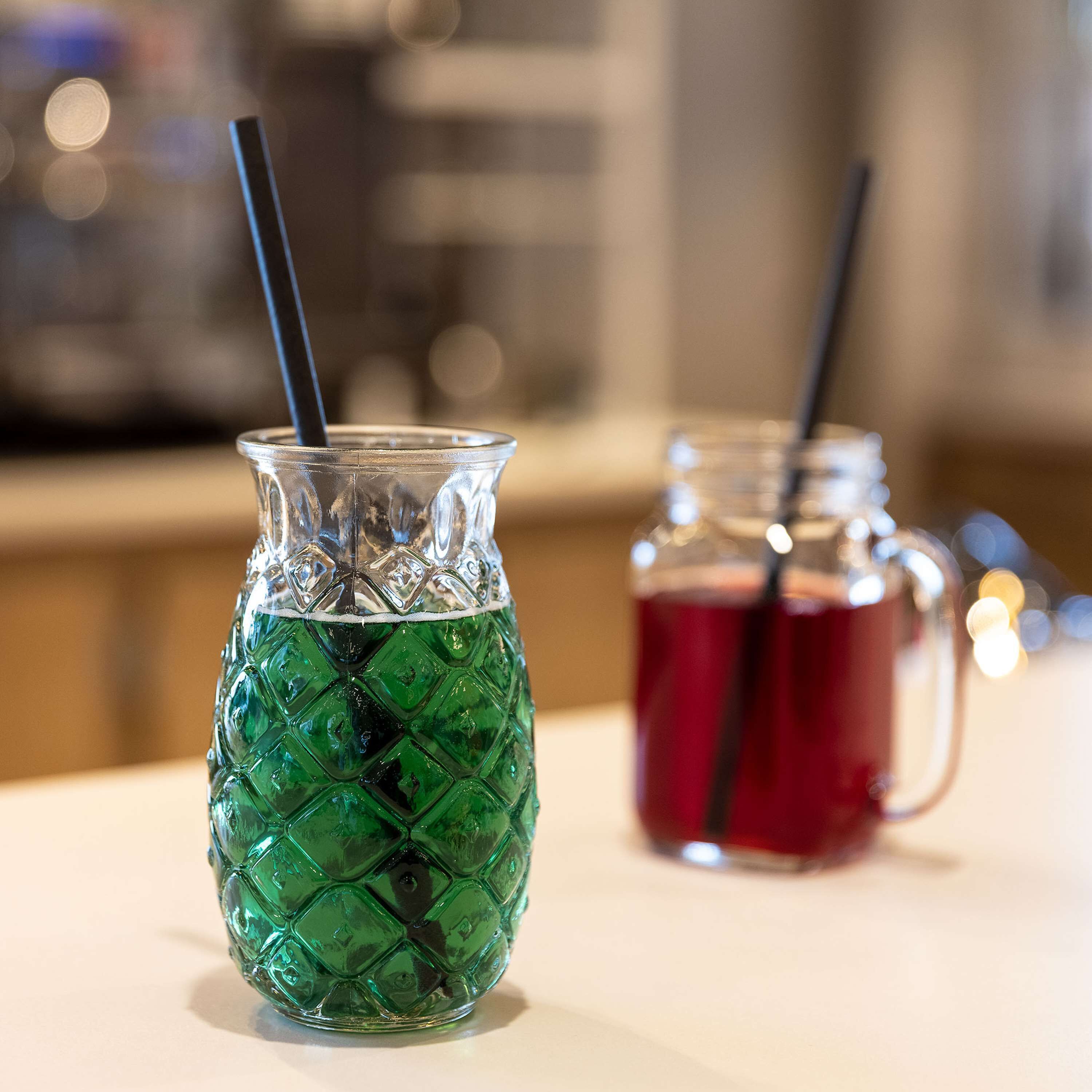 Two drinks in a glass and a mug on a table.