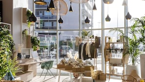 Un espace de vente moderne doté de grandes fenêtres, de planchers en bois et de différents types de luminaires suspendus.