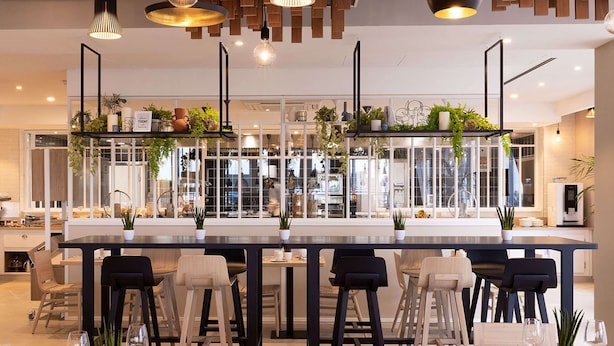Une cuisine moderne dotée d’un îlot central, de tabourets de bar et de luminaires suspendus.