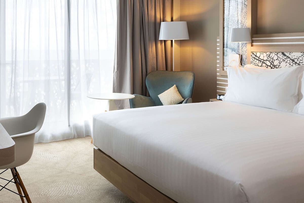 Une chambre d’hôtel avec un grand lit, une chaise, une petite table et une lampe.