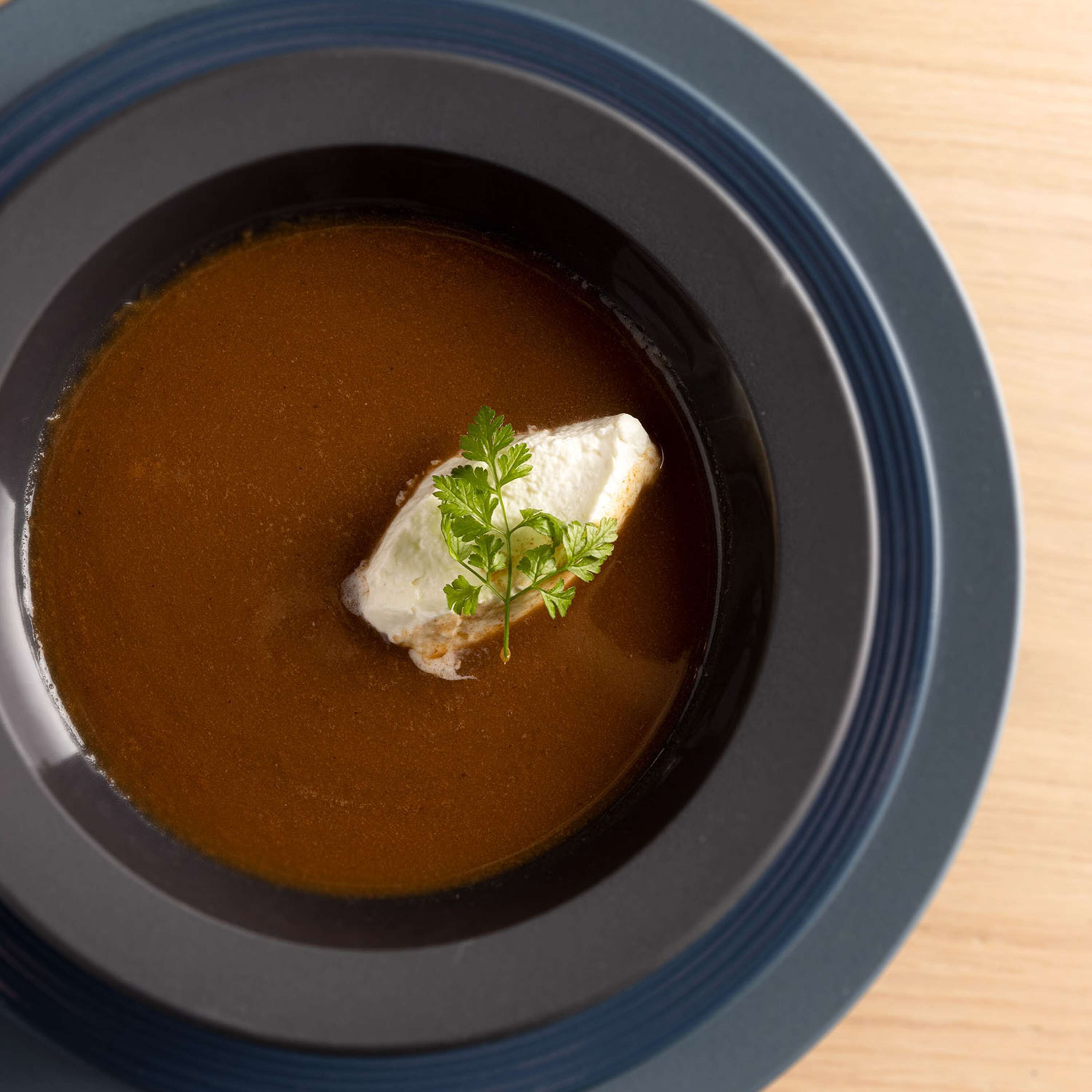 A bowl of soup with a piece of fish and a garnish.