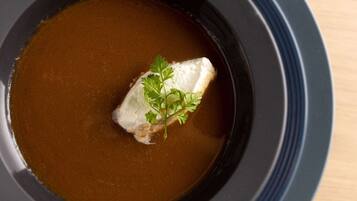 A bowl of soup with a piece of fish and a garnish.