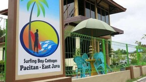 Señal de Surfing Bay Cottages en Pacitan, Java Oriental, con una escena de playa tropical.