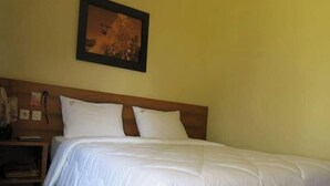 Una cama bien tendida con ropa blanca, cabecera de madera y un cuadro en la pared.