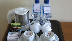 Una bandeja con una cafetera, dos botellas de agua, un paquete de café Nescafé, un paquete de café Krim y dos tazas con sus platillos.