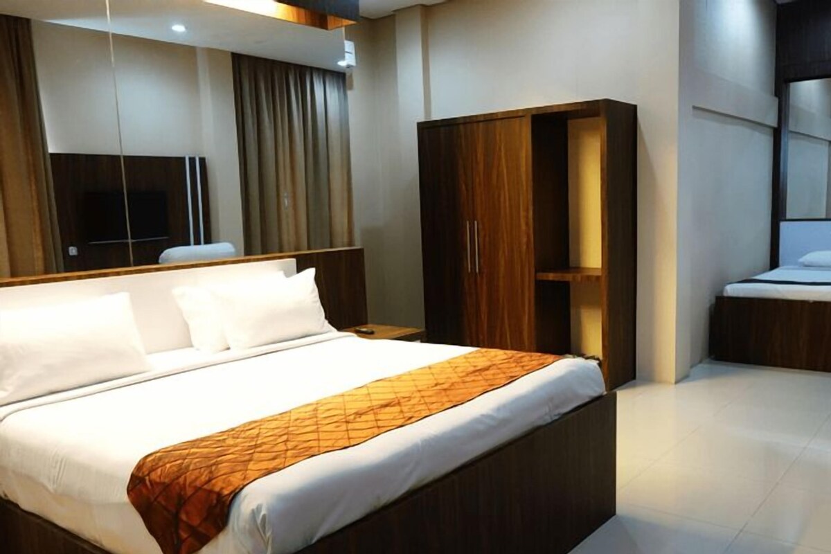 Une chambre d’hôtel avec un grand lit, une armoire, une télévision et un miroir.