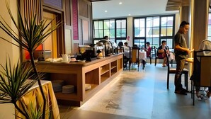 L’intérieur d’un restaurant moderne, avec un long comptoir, de nombreuses tables et de grandes fenêtres.
