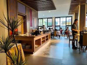 L’intérieur d’un restaurant moderne, avec un long comptoir, de nombreuses tables et de grandes fenêtres.