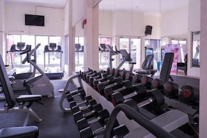 Une salle de sport équipée de tapis de course, d’appareils de musculation et d’haltères.