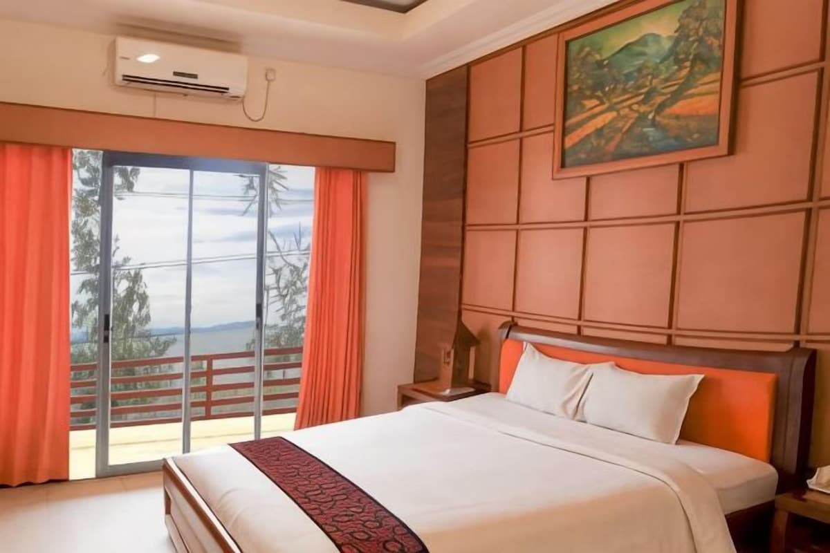 Habitación de hotel con una cama grande, un cuadro en la pared y vistas a través de la ventana.