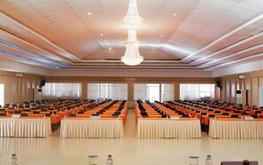 A large conference room with rows of tables and chairs, a chandelier, and large windows. - Sutan Raja Hotel Kolaka (Kolaka)