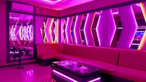 A modern interior with a pink-lit seating area, a glass partition, and a reception desk. - Sutan Raja Hotel Kolaka (Kolaka)