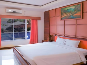 A hotel room with a bed, a window with a view of a pool, and a painting on the wall. - Sutan Raja Hotel Kolaka (Kolaka)
