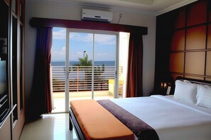 A hotel room with a bed, a bench, a television, and a view of the sea through a sliding door. - Sutan Raja Hotel Kolaka (Kolaka)