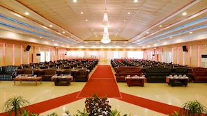 A large hall with rows of tables and chairs, a red carpet, and a chandelier. - Sutan Raja Hotel Kolaka (Kolaka)