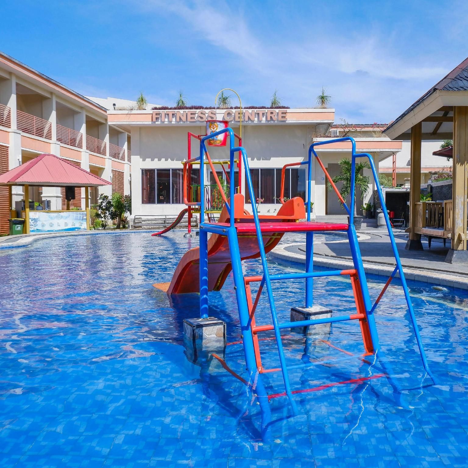 A swimming pool with a blue tiled floor, surrounded by a building labeled 'FITNESS CENTRE'.