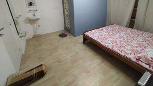 A bedroom with a bed, a small sink, an air conditioner, and a mirror.