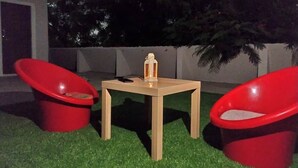 A small outdoor seating area with a table and two red chairs.