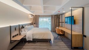 Habitació d'hotel moderna amb llit, escriptori, cadira i televisió penjada a la paret.
