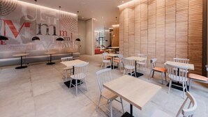 Una cafeteria moderna amb taules i caires blanques, una paret gran amb text i una paret de panells de fusta.