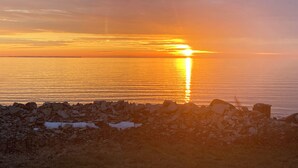 A sunset over a calm sea with rocky shoreline. - Sunset Cottage on Pillar Point (Dexter)
