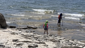 A rocky shoreline with two people standing in shallow water. - Sunset Cottage on Pillar Point (Dexter)