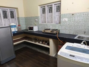 Compact kitchen with refrigerator, microwave, gas stove, sink, and water dispenser.
