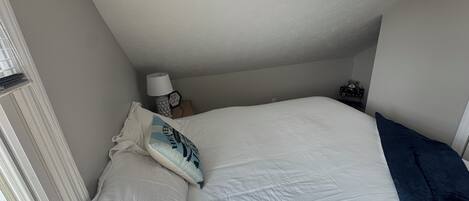 Et soveværelse med en stor seng, et vindue og et natbord med en lampe.