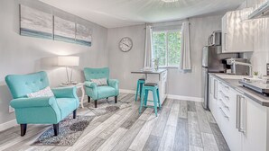 A modern kitchen with a dining area, featuring teal chairs, a chandelier, and a view of greenery outside. - Lighthouse Inn & Suites Extended Stay
Boutique Hotel I-69 Exit 334 (Waterloo)