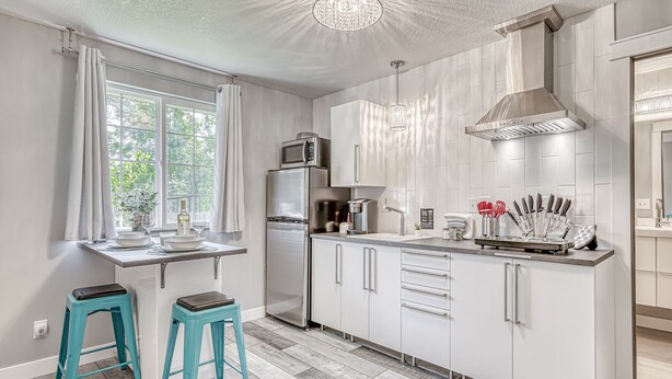 A modern kitchen with white cabinetry, stainless steel appliances, and a window with curtains. - Lighthouse Inn & Suites Extended Stay
Boutique Hotel I-69 Exit 334 (Waterloo)