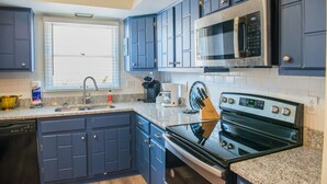 A kitchen with blue cabinets, a stainless steel microwave, a dishwasher, and a granite countertop. - Heart of the Bluegrass close to all attractions in Central Kentucky (Lexington)