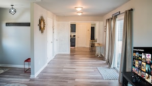 A spacious living room with a wooden floor, a television displaying movie options, and a dining area with a table and chairs. - Heart of the Bluegrass close to all attractions in Central Kentucky (Lexington)