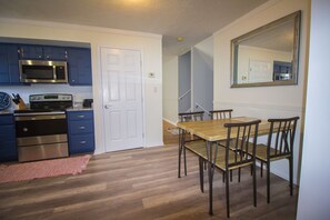 A modern kitchen with blue cabinets, stainless steel appliances, and a wooden dining table with chairs. - Heart of the Bluegrass close to all attractions in Central Kentucky (Lexington)